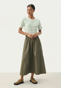 T-shirt a righe, maniche corte, verde menta e crema, abbinato a una gonna verde oliva alla caviglia con vita elastica e sandali marroni.