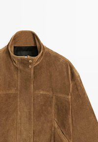 Bruine suède jas met hoge kraag, voorrits die verborgen is onder een met knopen afgesloten klep, en schuine zijzakken.