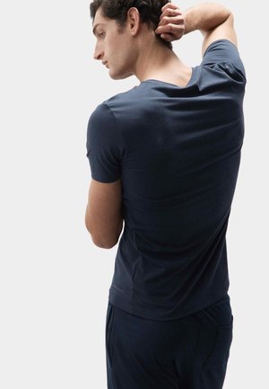 T-shirt aderente blu navy a maniche corte, texture liscia, con scollatura a V e un dettaglio del logo discreto vicino all'orlo.