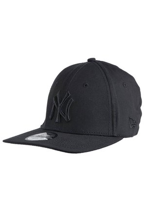 Sort New York Yankees baseballkasket med flad skygge og hævet syet logo foran, set fra front venstre vinkel.