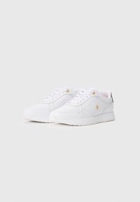 Ζεύγος λευκών χαμηλών sneakers με χρυσές λεπτομέρειες και κορδόνια, τοποθετημένα σε λευκό φόντο.