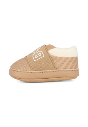 Tan toddler slip-on shoe with a soft lining, elastic strap, textured fabric, and smooth sole. Features logo detail on the strap.