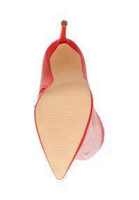 Scarpa rossa con tacco alto e punta affusolata, realizzata in pelle liscia, con una suola nude texturizzata. Presenta un elegante dettaglio metallico sul tacco.