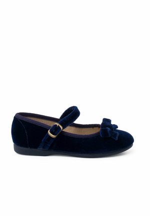 Zapato Mary Jane de terciopelo azul marino con punta redonda, correa ajustable con hebilla dorada y adorno de lazo en la parte delantera. Diseño de suela plana.