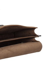 Interieur van een bruine suède handtas met twee compartimenten. Zachte textuur, gladde randen en een discreet metalen drukknoopsluiting.