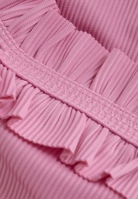 Pink fabric with ribbed texture and gathered ruffle accents along the edge. Features smocked detail at the top for added design.
