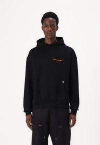 Schwarzer Kapuzenpullover mit orangefarbenem gesticktem Text "don't waste culture", ausgestattet mit einer Kängurutasche sowie gerippten Bündchen und Saum.