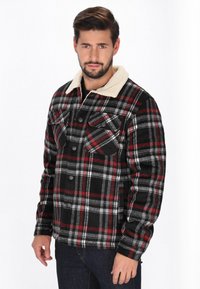 Piros, fekete és szürke kockás flanel dzseki, krémszínű gyapjú gallérral, két mellzsebbel és gombos záródással.