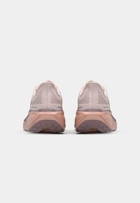 Zapatillas deportivas de color rosa claro con una parte superior de malla transpirable, suela acolchada y suela exterior de goma texturizada. Presentan un talón trasero redondeado.