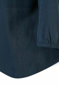 Blouse bleu foncé en tissu doux et texturé, avec une coupe décontractée, des poignets élastiques et un ourlet arrondi. Matériau lisse et léger.