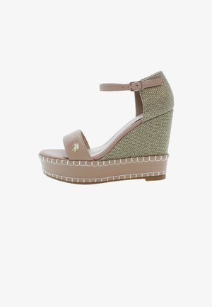 Sandały na koturnie w beżowej skórze z teksturowanym zielonym, plecionym obcasem. Posiadają przedni pasek, pasek na kostkę i białe szwy.
