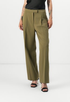 Olive green tailored trousers with pleats, high waistband, and a wide-leg design. Paired with black heeled sandals. Smooth texture.