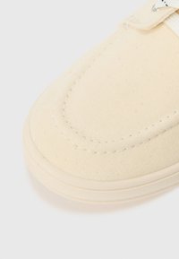 Lærrets slip-on sko i off-white. Har en teksturert overflate, rund tå, sømdetaljer og gummisåle.