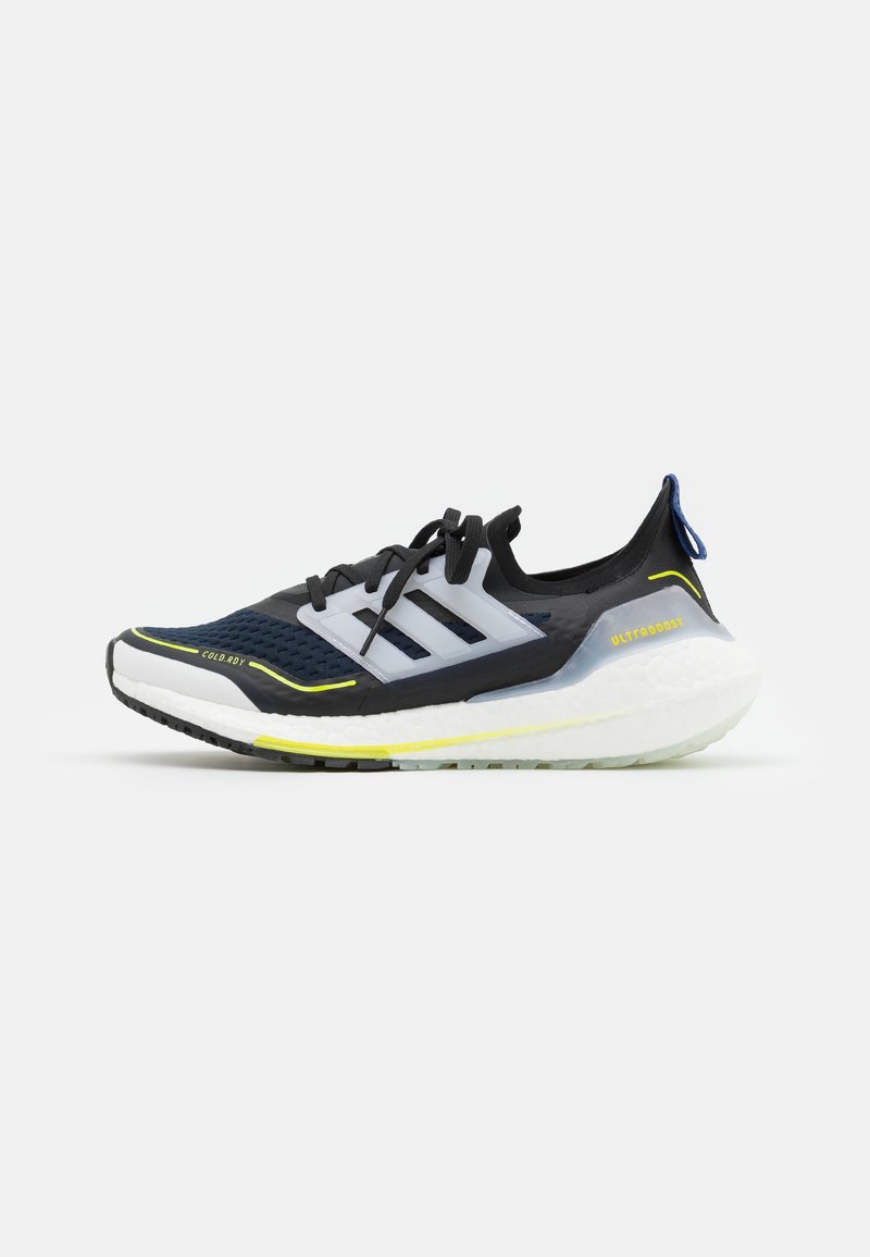 Černá běžecká obuv s prodyšným síťovaným svrškem, bílou mezipodešví, neonově žlutými akcenty a modrou poutkovou záložkou na patě. Obsahuje branding ve tvaru tří pruhů.