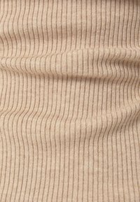 Tissu beige à côtes avec des lignes verticales étroites, texture douce et léger brillant. Le motif crée un effet visuel en couches.