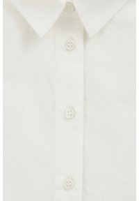 Balti medvilniniai marškiniai su standartiniu apykakle ir plokštele su šešiomis sagomis, iš kurių dvi yra dekoratyvinės. Lygus tekstūras ir klasikinis dizainas.