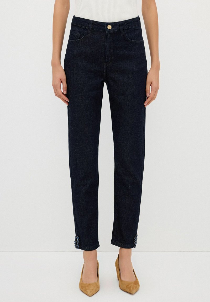 Jeans de denim azul oscuro con cintura alta, diseño de pierna recta, que cuentan con detalles decorativos en los puños y un cierre delantero de botones.