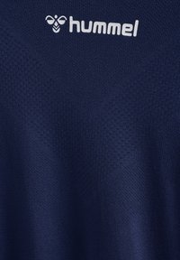 Marint blå atletisk tröja gjord av texturerad, andningsbar tyg. Har en V-halsdesign och en vit "hummel"-logotyp på bröstet.