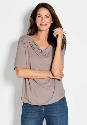 Korte mouwen, gedrapeerde top in licht taupe stof, met een V-halsontwerp en een relaxed fit, gecombineerd met blauwe denim jeans.