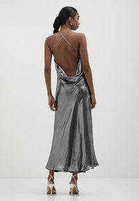 Silbernes Satin-Midi-Kleid mit einem Schlüsselloch-Ausschnitt, dünnen gekreuzten Trägern und einem fließenden Rock. Auffälliger Glanz und weiche Textur. Elegantes Design.