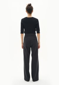 Top negru, cu dungi fine, cu mâneci scurte, asortat cu pantaloni negri, cu talie înaltă și croială largă. Design minimalist, textură netedă, fără modele vizibile.