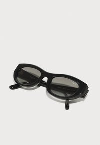 Black sunglasses with angular frames and gray lenses. The design features a glossy finish and logo detail on the inner arm.