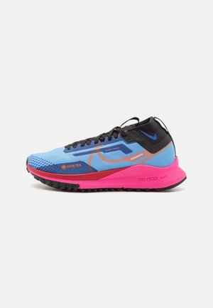 Blauer und pinker Nike Trailrunning-Schuh mit schwarzen Schnürsenkeln, Gore-Tex-Label und Nike React-Sohle vor weißem Hintergrund.