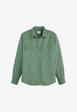 Camicia verde a maniche lunghe in tessuto morbido. Presenta due tasche sul petto, maniche lunghe con polsini a bottone e un colletto classico.