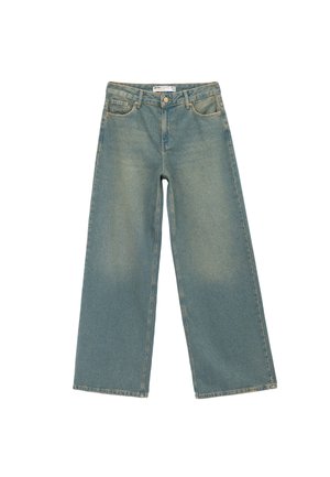 Jeans en denim bleu clair à jambes larges, présentant une finition délavée, quatre poches et une fermeture à bouton. Détail d'ourlet brut en bas.