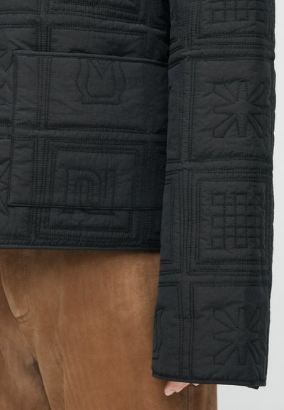 Kleeditud must jakk, millel on reliefne muster, lahtine lõige ja voolujooneline disain. Kangas näeb välja tekstuuritud ja kerge.