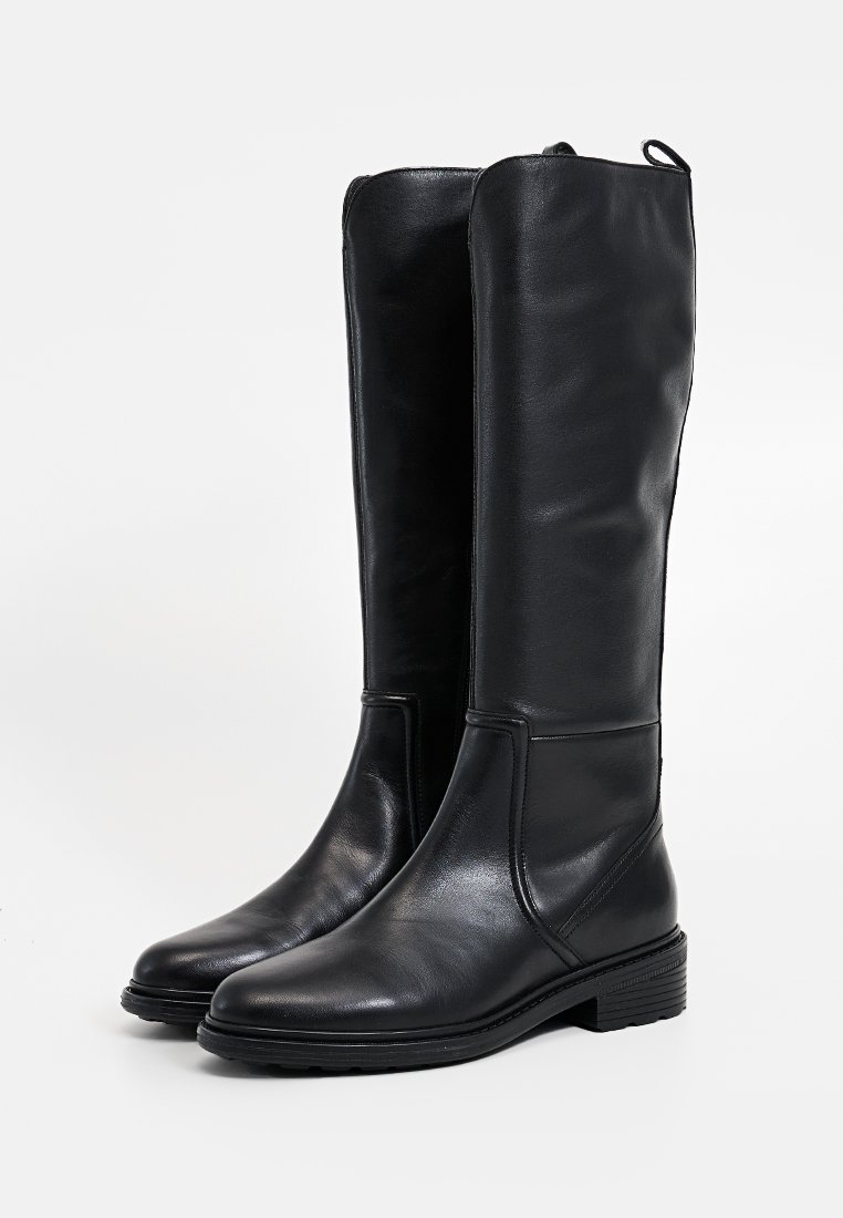 Botas altas de cuero negro con un acabado suave, punta redondeada y tacón bajo tipo bloque. Cuentan con una lengüeta en la parte posterior para facilitar su uso.