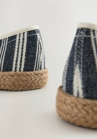 Blauw en wit gestreepte canvas espadrille met een natuurlijke jute touwzool. Heeft een ronde neus en gestikte details langs de randen.
