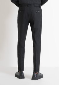 Pantaloni neri con una vestibilità comoda, vita elastica e due tasche posteriori. Abbinati a sneakers nere con suole texturizzate.