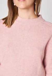 Maglione a maglia rosa chiaro con un collo alto e texture sottile, dotato di una cucitura centrale sul davanti. Tessuto morbido con una vestibilità rilassata.