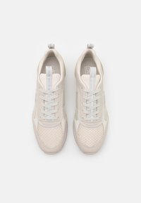 Pair of beige mesh and leather sneakers with light blue striped pull tabs and white shoelaces, viewed from above on white background.