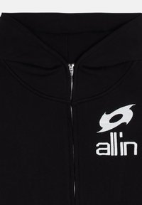Haut de hoodie zippé noir avec un grand logo blanc, doté d'une capuche et d'une texture de tissu lisse, avec une fermeture éclair argentée visible sur le devant.