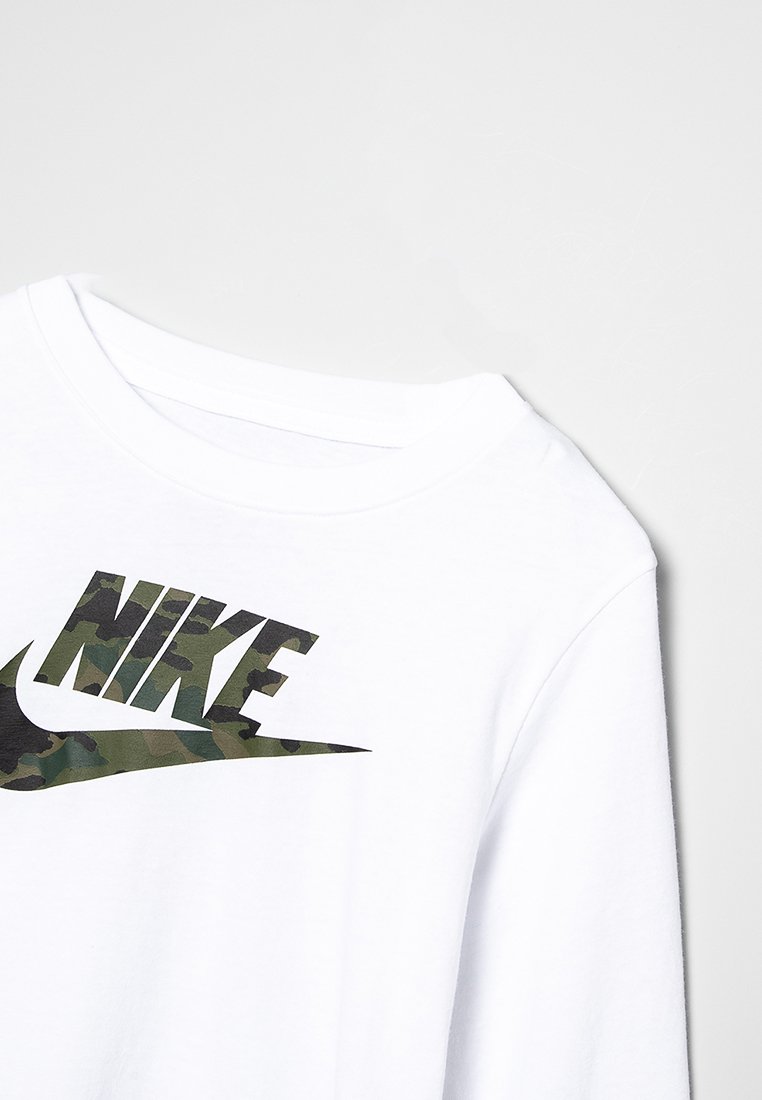 Chemise blanche à manches longues avec un grand logo Nike camouflage noir et vert sur le devant. Matière en coton doux avec un col rond.