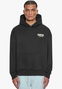 Black hooded sweatshirt made from soft fabric, featuring a front pocket and a "DROP SIZE Studios" logo in white on the left chest.