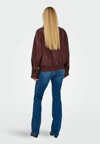 Giacca di pelle bordeaux con una vestibilità comoda, vita elastica e maniche lunghe, abbinata a jeans a zampa d'elefante blu e stivali neri con tacco.