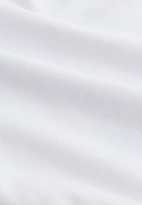 Közelkép sima fehér szövetről, melyen finom horizontális redők láthatók, kiemelve a finom textúrát és szövést.