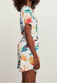 Korte mouwen romper van lichtgewicht stof met een witte basis en kleurrijke bloemen- en fruitpatronen. Het heeft een ontspannen pasvorm en een riem in de taille.