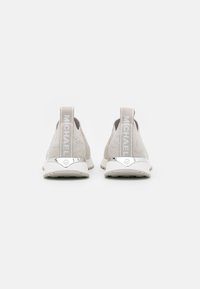 Baskets gris clair avec un dessus texturé, des tirettes étiquetées "MICHAEL" et une semelle blanche contrastante avec des accents métalliques.