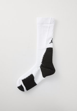 Witte sportsok met zwarte gestructureerde accenten, voorzien van eencompressiegebied en een zwart Jumpman-logo; geribbelde boord voor extra ondersteuning.