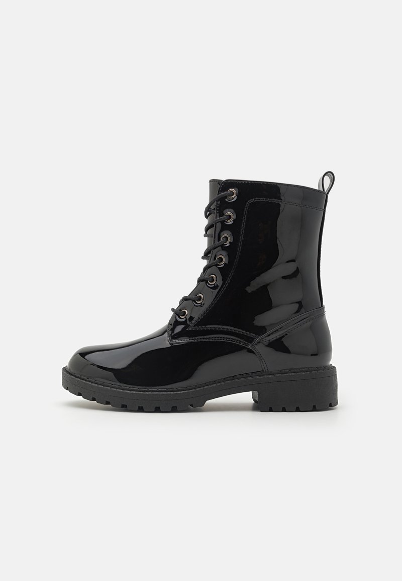 Botines de charol negro con cordones en la parte delantera, puntera redonda y suela de goma resistente. Presentan ojales metálicos y una cinta de tirón.