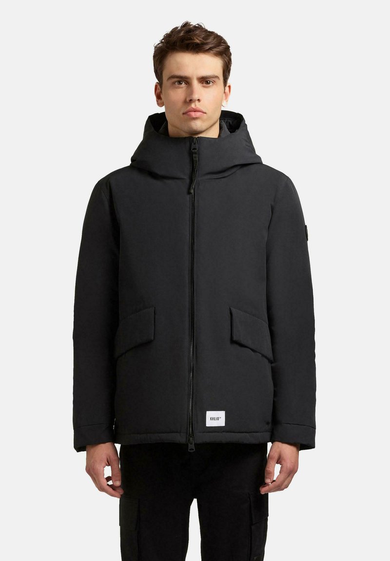 Schwarze gepolsterte Jacke mit Kapuze, Reißverschluss, zwei Fronttaschen und einem Etikett am Saum. Glatte Textur und lässige Passform.