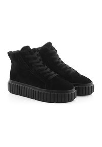 Zwarte suède hoge sneakers hebben een dikke, gegroefde zool, een vetersluiting aan de voorkant en een nepbonten voering bij de kraag.