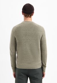 Grijs-groen gebreid sweater met een ronde halslijn en lange mouwen, met een gestructureerde afwerking. Draag met een donkere beanie.