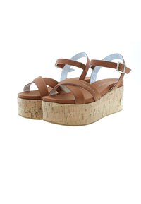 Hnědé kožené platformové sandály s korkovou podrážkou, s překříženými pásky a nastavitelným řemínkem kolem kotníku. Hladký povrch a minimalistický design.