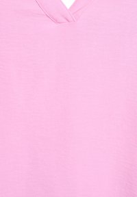 Top rosa chiaro con scollo a V realizzato in un tessuto morbido e testurizzato; presenta un design semplice senza motivi né dettagli in metallo.