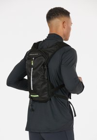 Black mesh backpack featuring reflective accents, adjustable straps, and a zippered front pocket, designed for sports and outdoor activities.